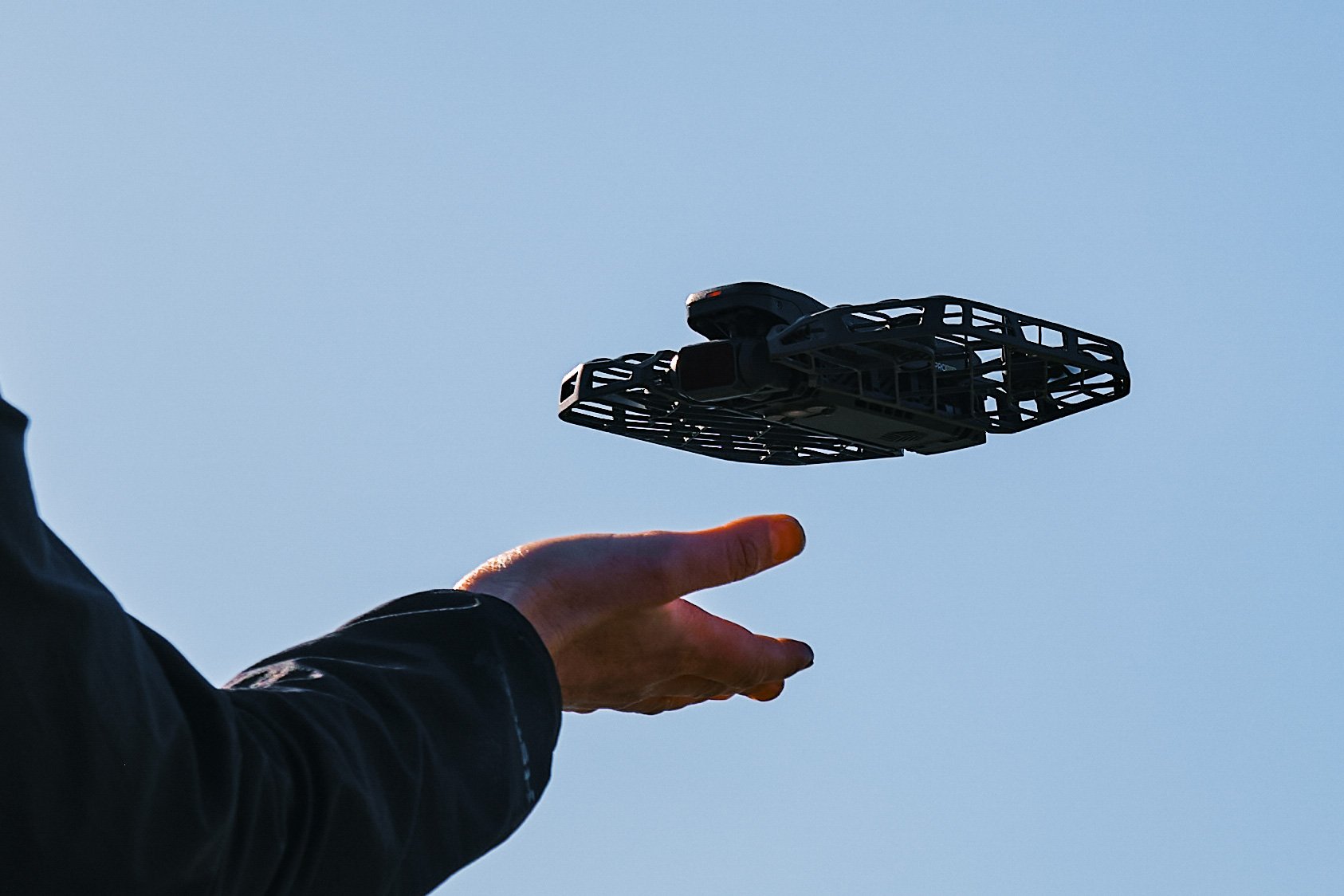 A HOVERAir X1 PROMAX foldable drone taking off from a person's hand.