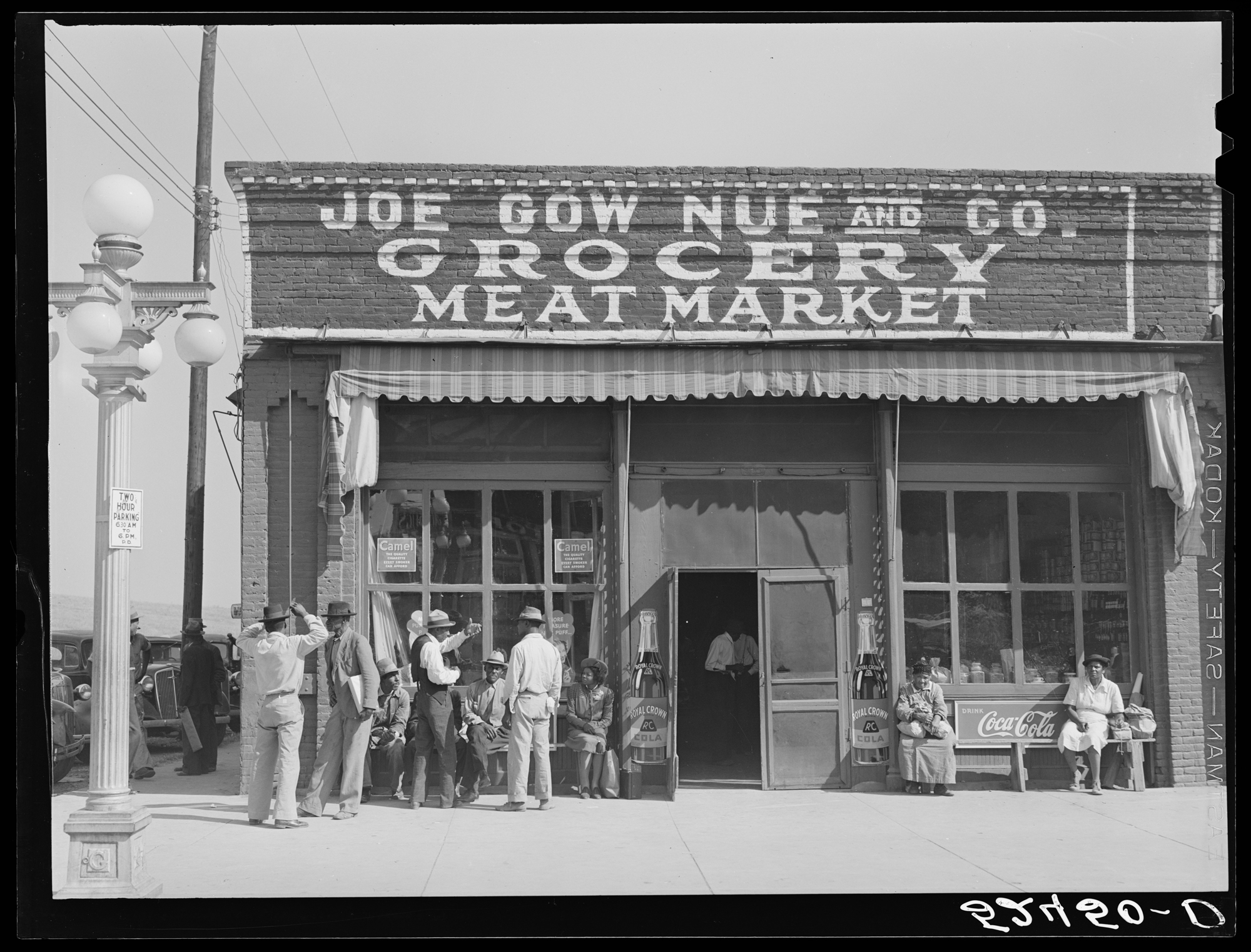 A photograph by Marion Post Wolcott of Black customers outside a Chinese American grocery store, taken in Leland, Mississippi in 1939. 